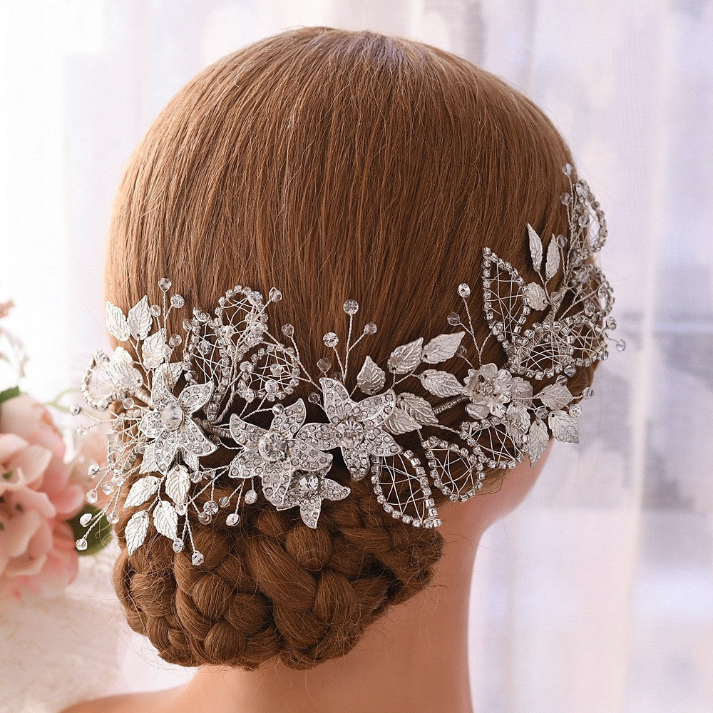 Elegant silver hairpiece with floral and leaf designs on a blurred background