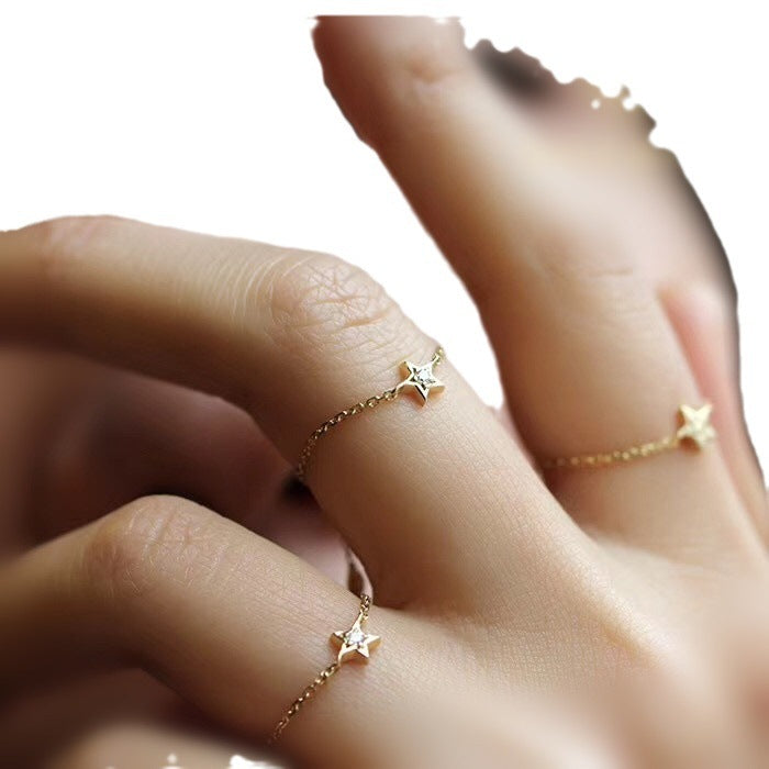 Gold star-shaped ring on a hand against a neutral background