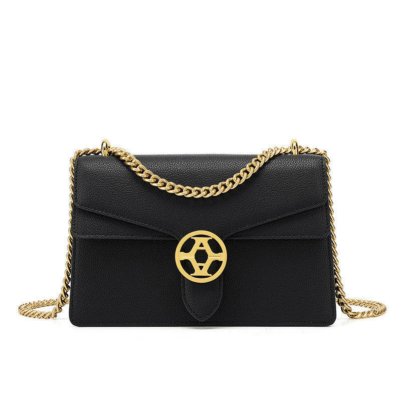 Black handbag with gold chain and emblem on a white background