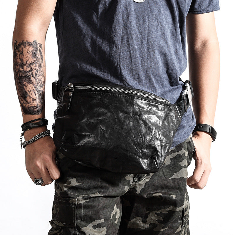 Person wearing a black leather waist bag, camouflage pants, and a blue shirt on a white background
