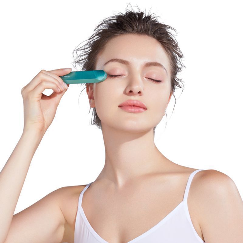 Woman using a jade roller on her face against a white background