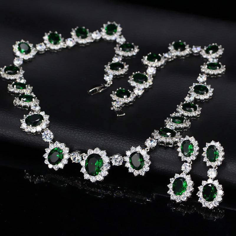 Jewelry set with emerald green gemstones and silver accents on a dark background
