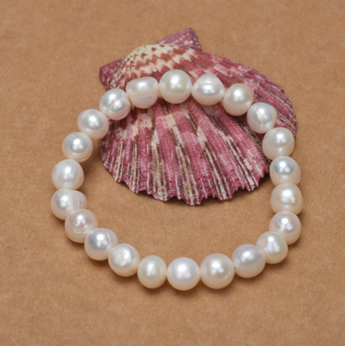 Pearl bracelet on a pink shell against a brown background