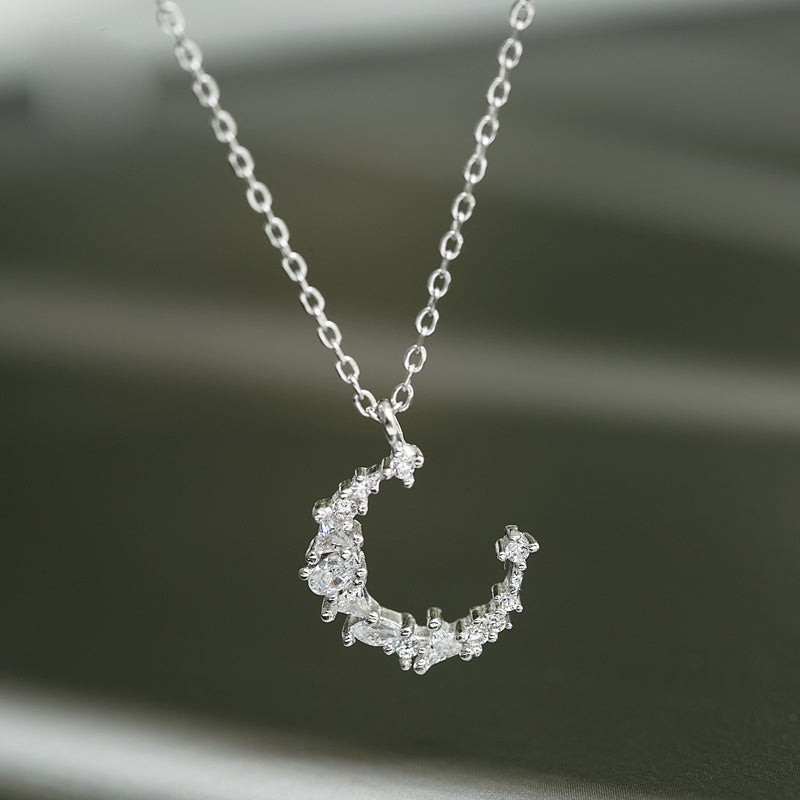 Silver necklace with a crescent moon pendant on a dark background