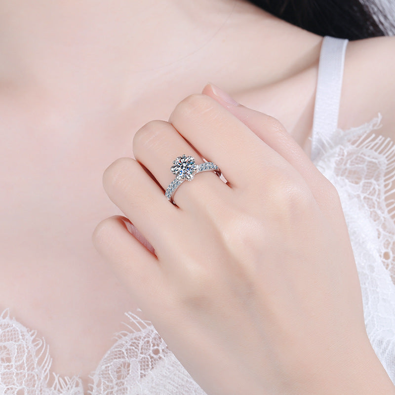 Silver ring on a finger with a blurred lace background