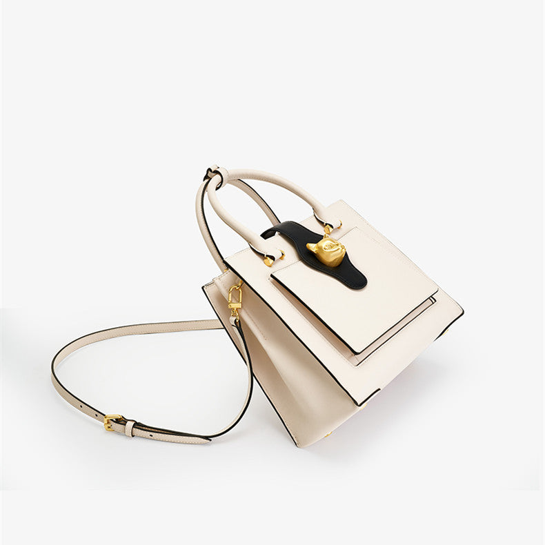 Beige handbag with black accents on a white background