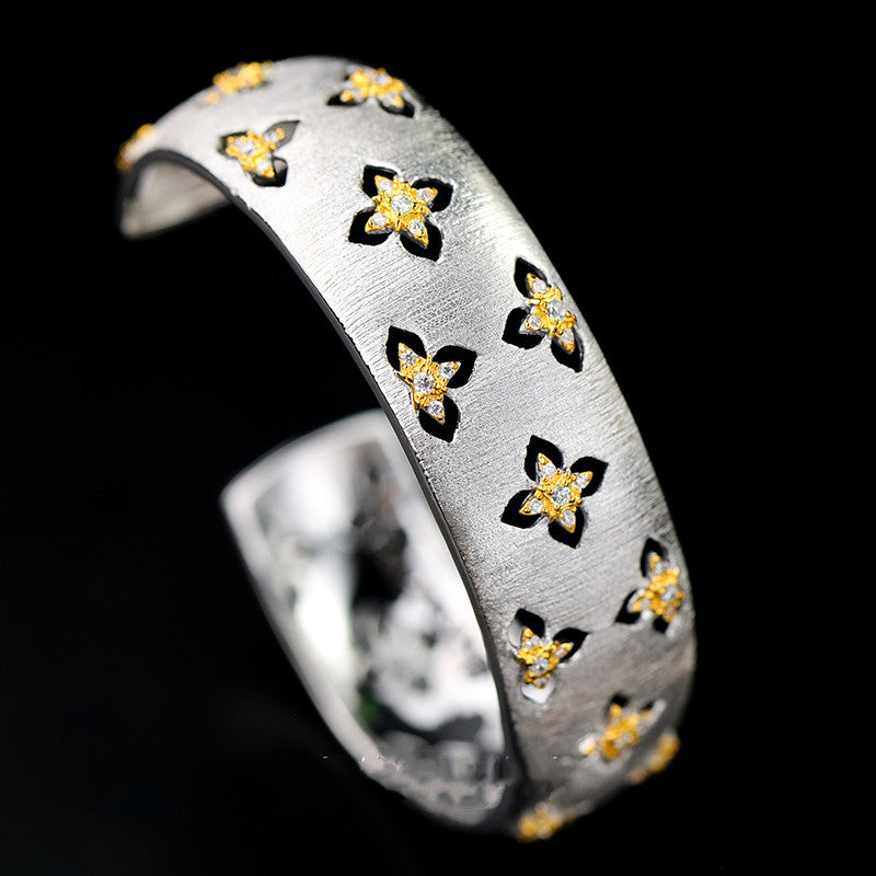 Silver ring with floral designs on a black background