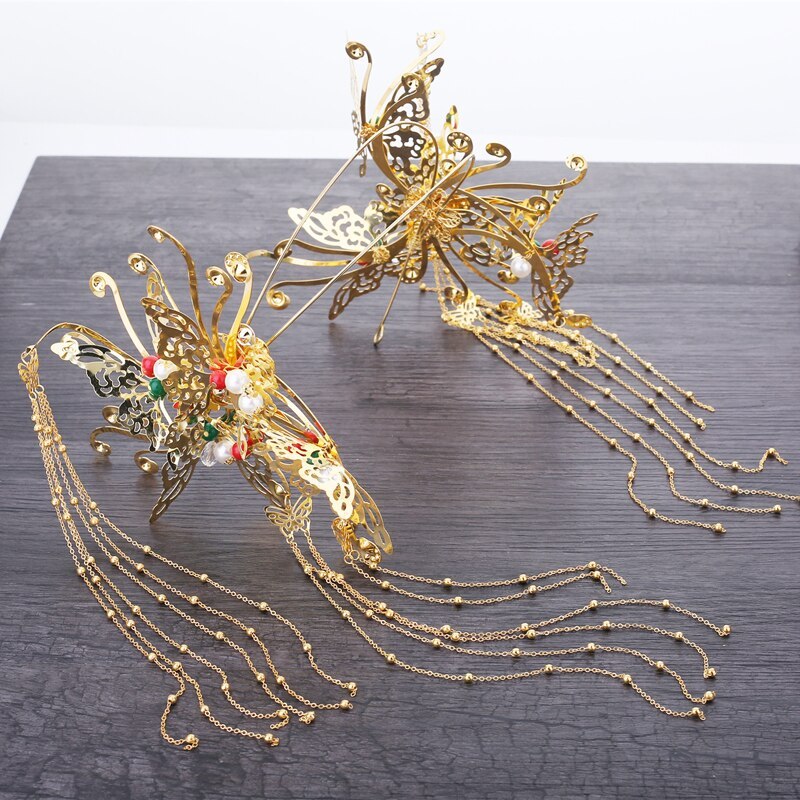 Gold butterfly hair accessories with decorative elements on a dark surface