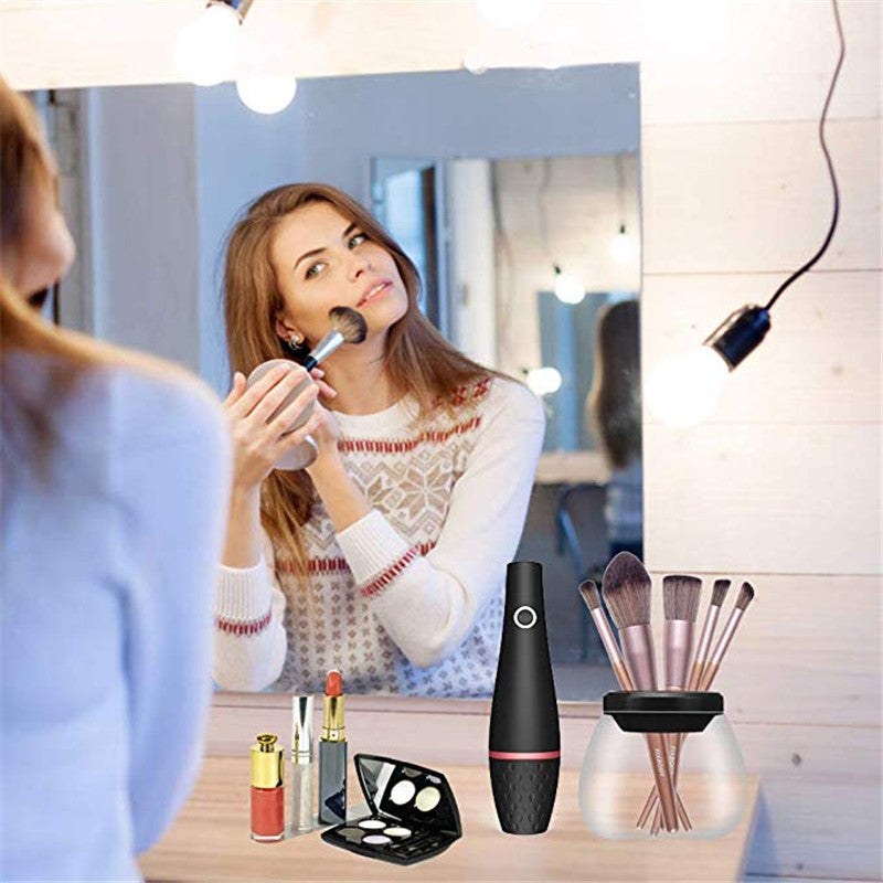 Woman applying makeup in front of a mirror with various cosmetic items on a table.