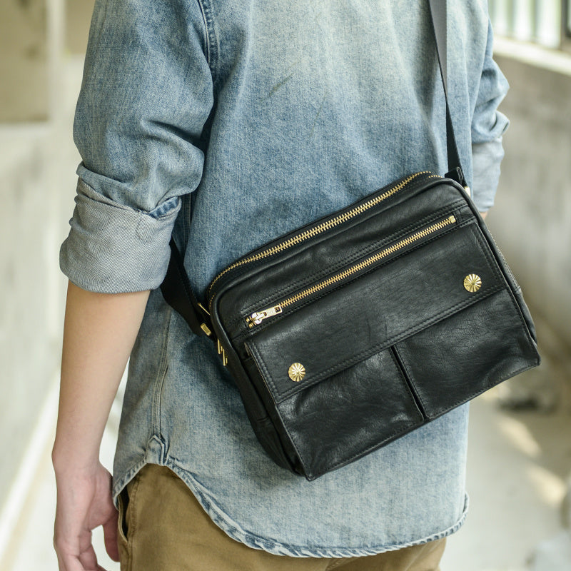 Person wearing a black leather bag with gold zippers and hardware.