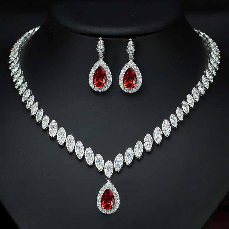 Jewelry set with necklace and earrings featuring red gemstones on a black background