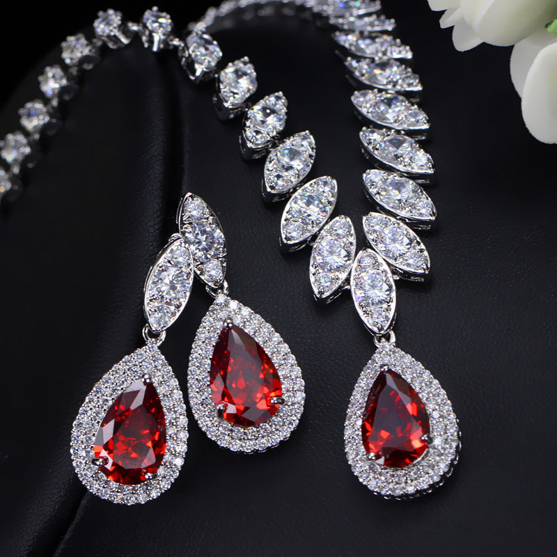 Jewelry set with red teardrop gemstones on a black background