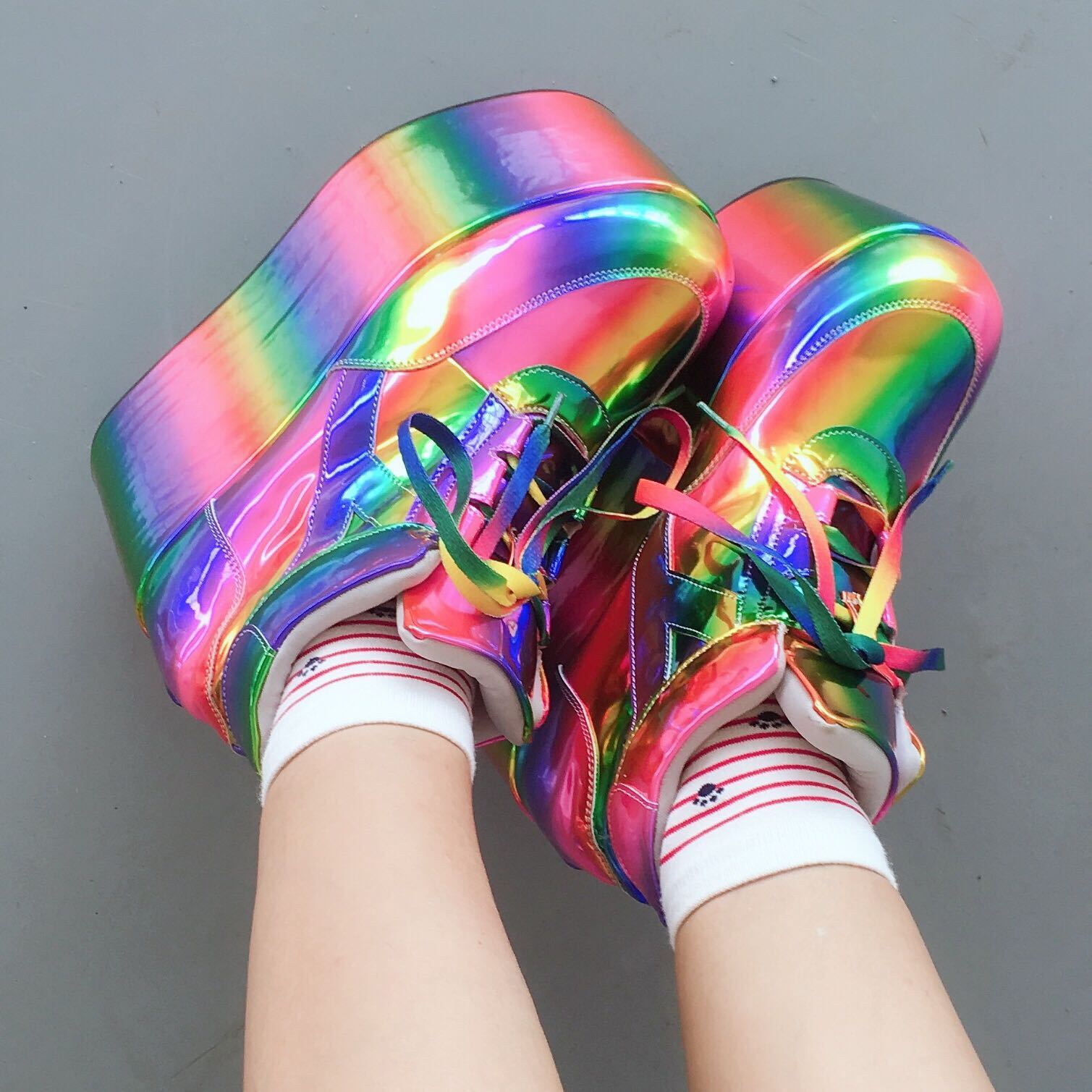Colorful platform shoes worn with white socks on a gray background