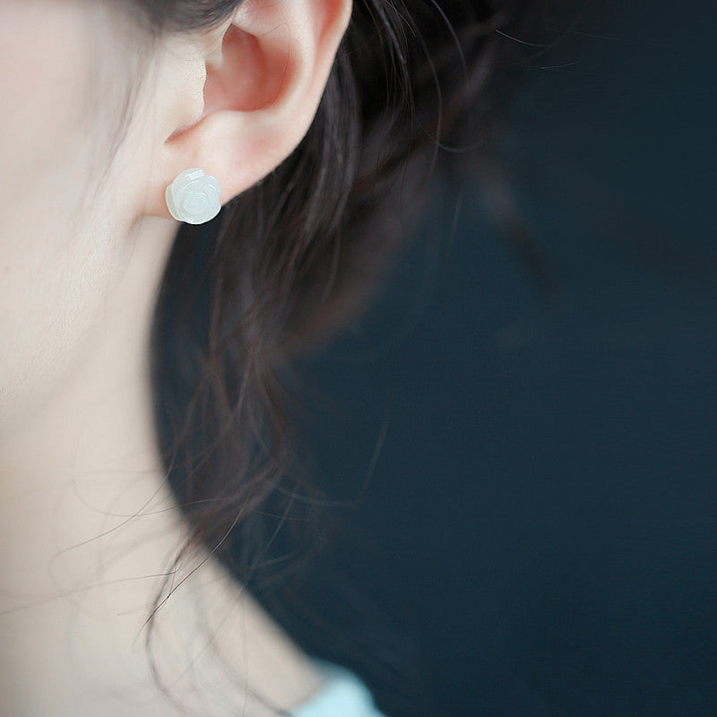 Close-up of an ear wearing a round earring with a dark background