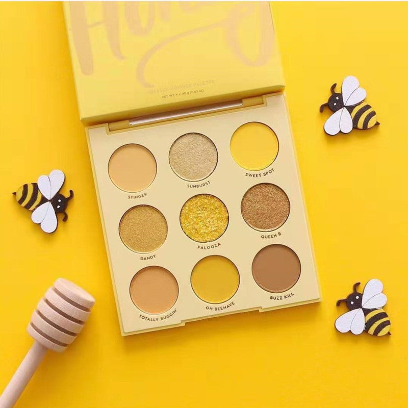 Makeup palette with yellow and brown shades on a yellow background with bee decorations