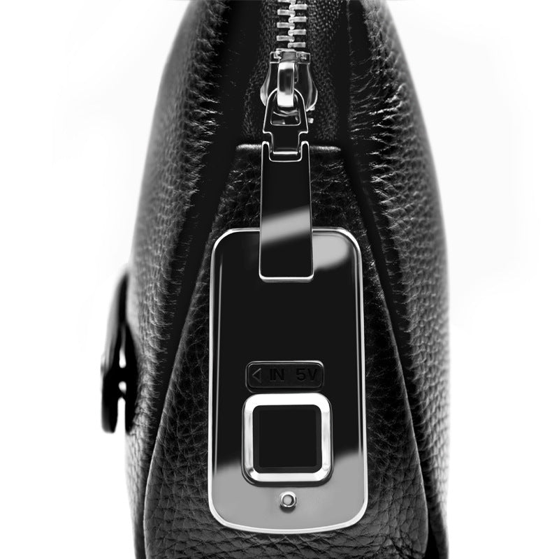Close-up of a black leather bag with a silver zipper and a key fob attached.