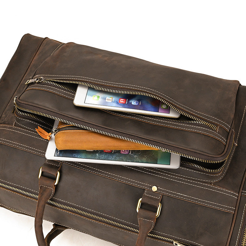 Brown leather briefcase with multiple compartments and a smartphone inside on a white background