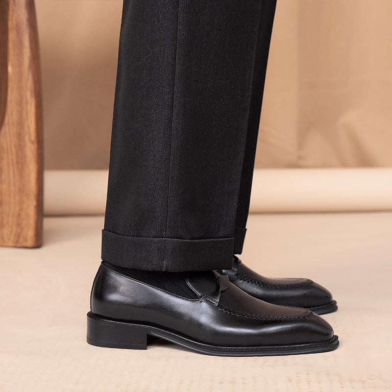 Black dress shoes and black pants on a beige background
