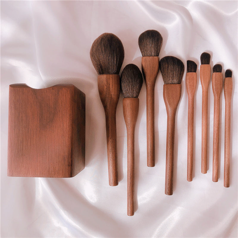 Set of wooden makeup brushes with a wooden holder on a white fabric background