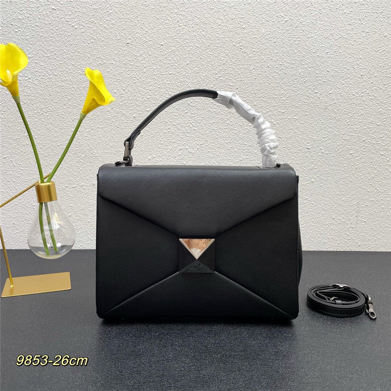 Black handbag with decorative handle on a dark surface with a light gray background
