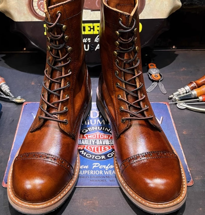 Pair of brown leather boots on a Harley-Davidson branded mat with tools in the background.