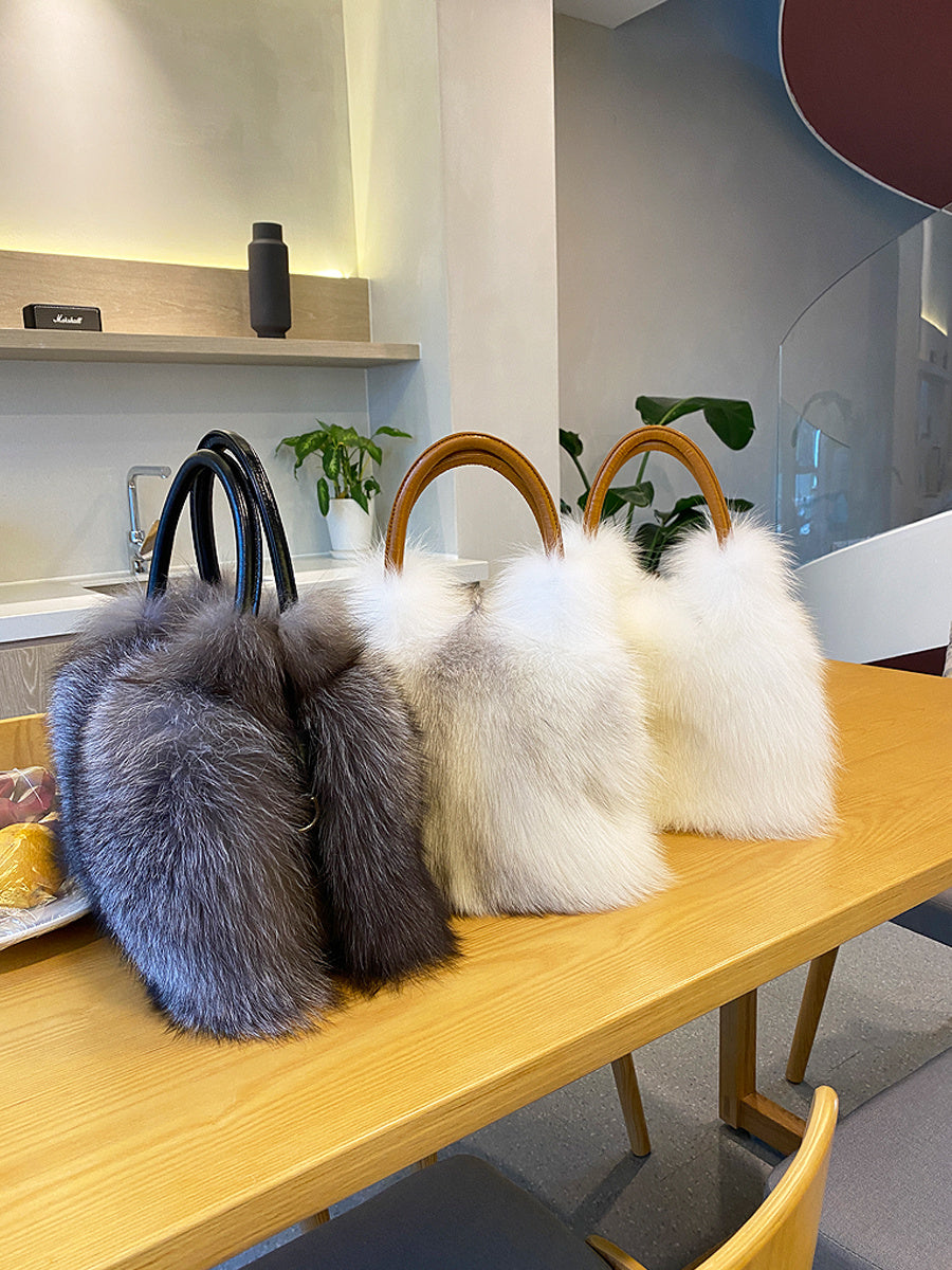 Three fur-lined handbags on a wooden table with a kitchen background