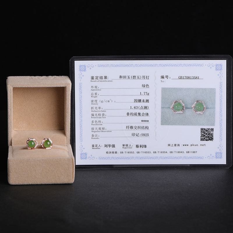 Green gemstone earrings in a box with a certificate on a black background