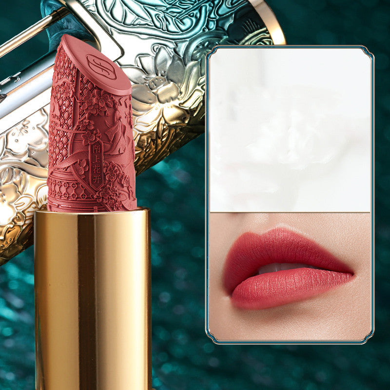 Lipstick with gold casing and decorative lid, shown open with a mirror reflection of lips.