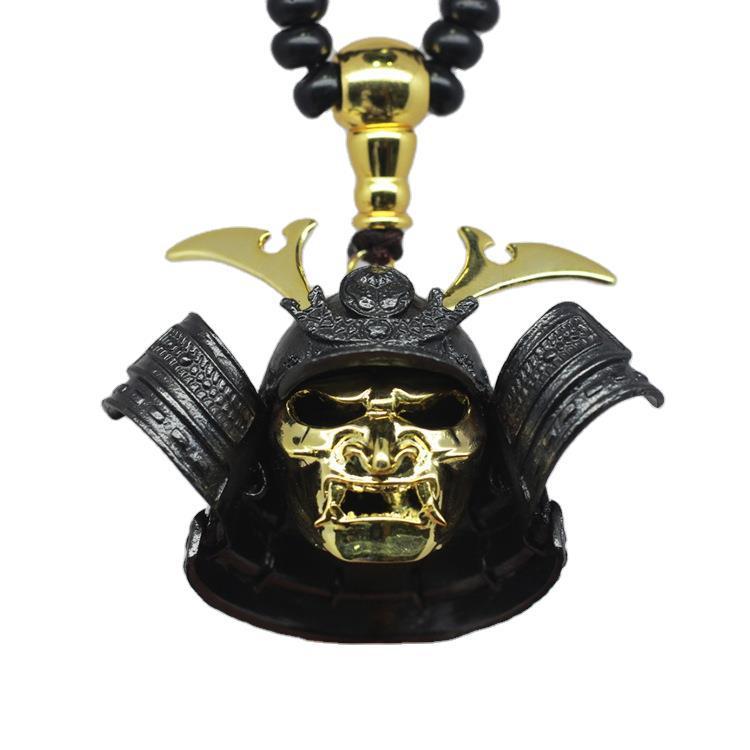 Skull pendant with gold accents on a black beaded necklace against a white background