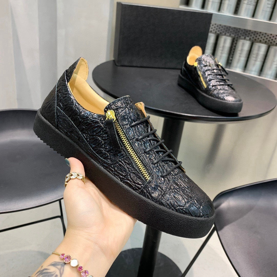 Black textured sneaker with a gold zipper held by a hand, with another sneaker on a table in the background.