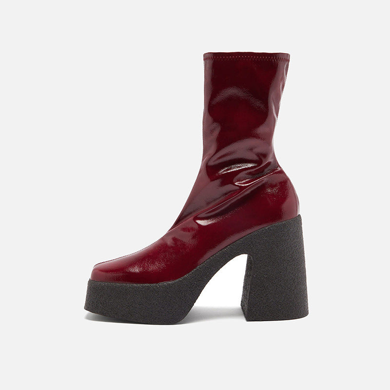 Red patent leather boot with a chunky black sole on a white background