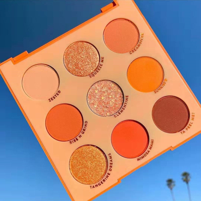 Makeup palette with orange and brown shades against a blue sky