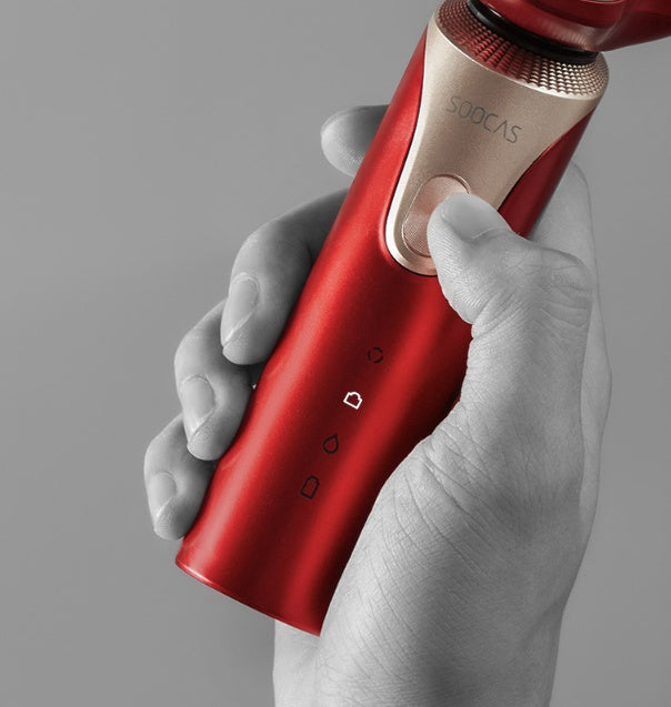 Red handheld device with 'Socas' branding held by a hand against a gray background