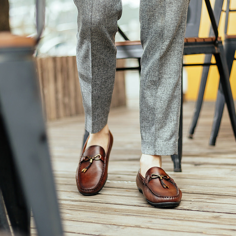 Person wearing brown loafers and gray pants on a wooden deck.