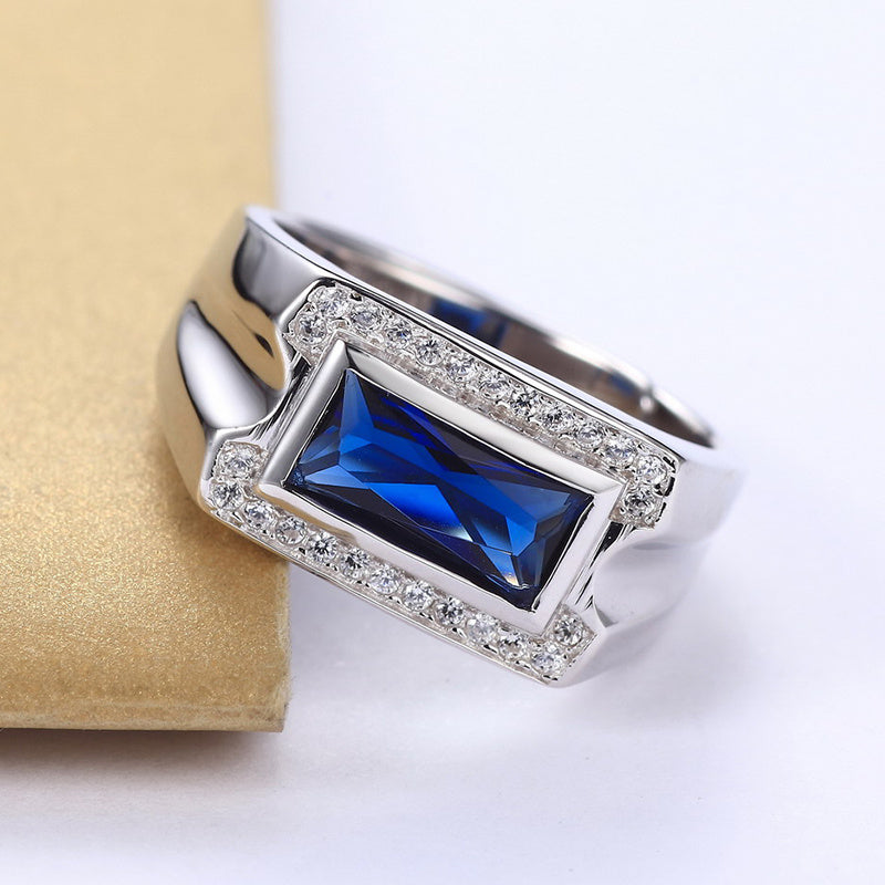 Silver ring with a blue gemstone on a beige cushion