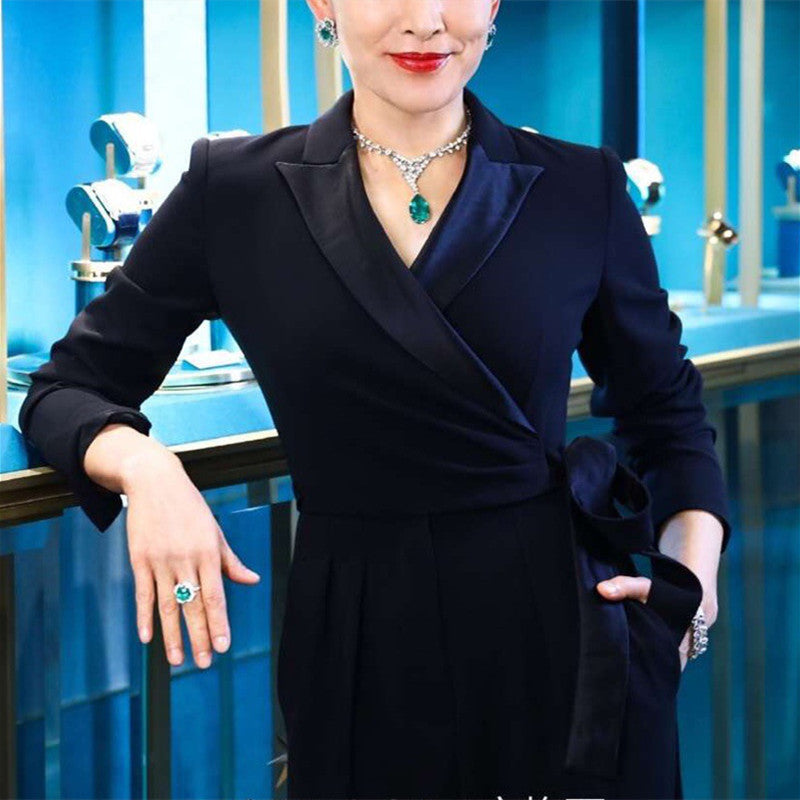 Woman in a black outfit with jewelry against a blue background