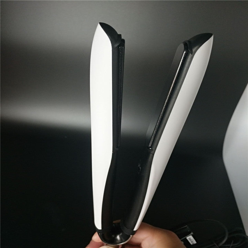 Hair straightener held by a hand against a dark background