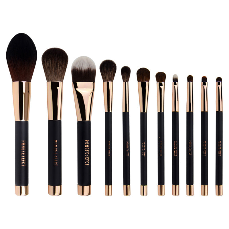 Set of makeup brushes with black handles and rose gold ferrules on a white background