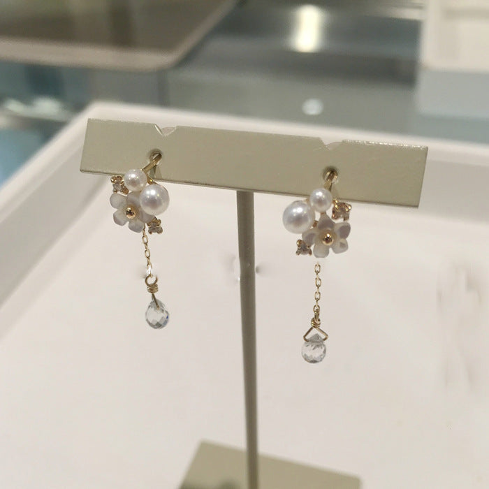 Pair of pearl earrings on a display stand with a neutral background