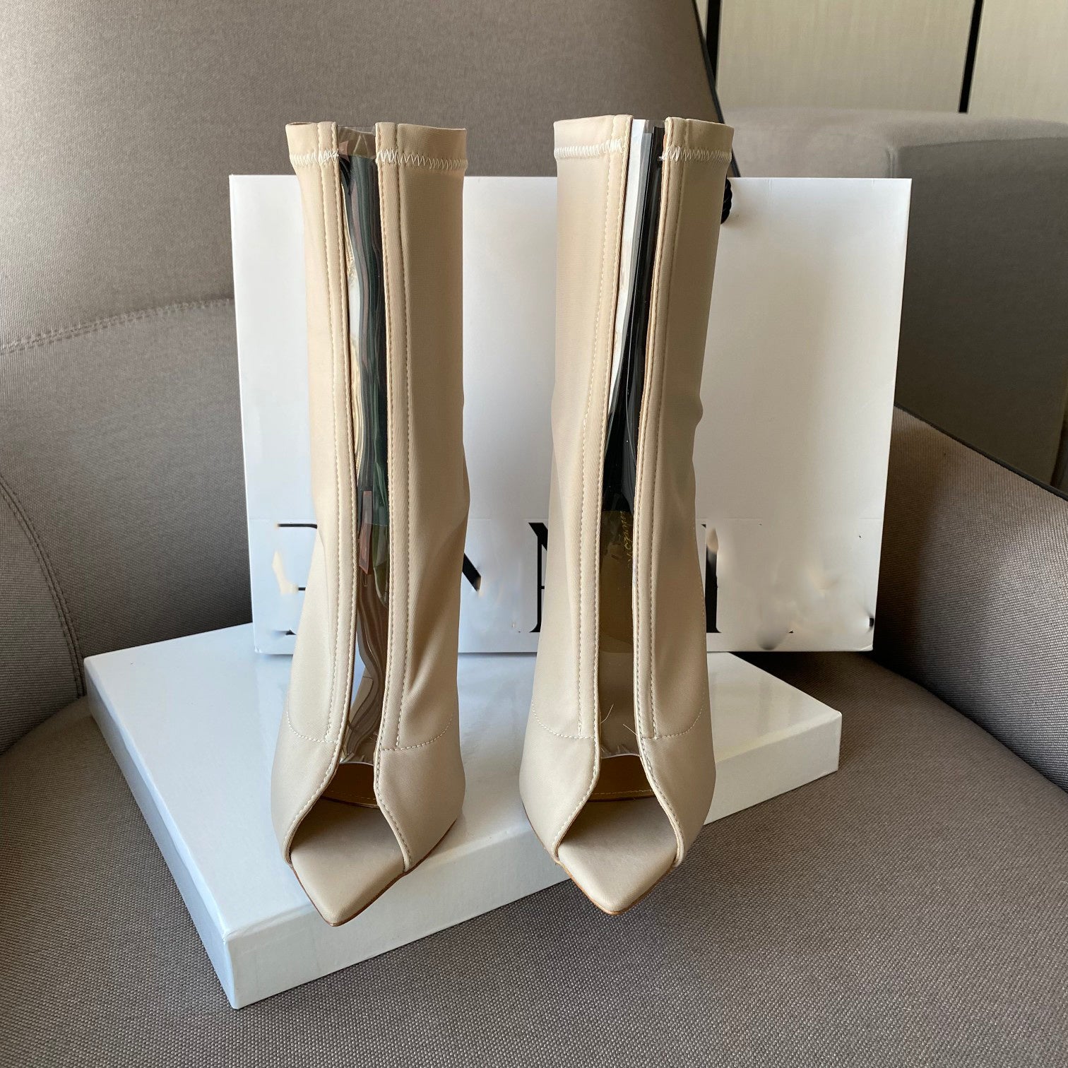 Beige high-heeled boots on a white platform with a neutral background