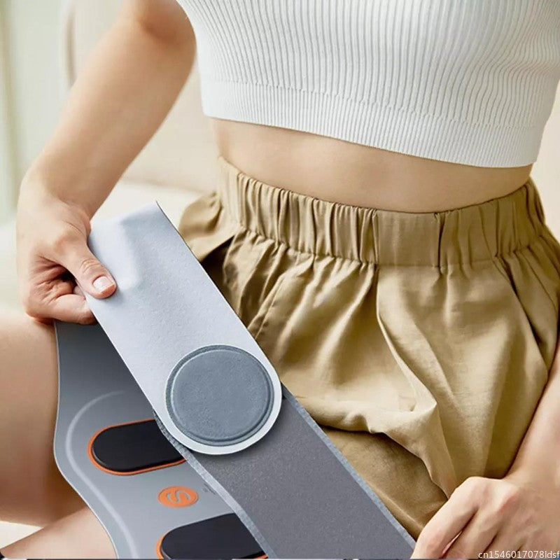 Person holding a gray electronic device with a digital display and button, wearing a white top and beige pants.