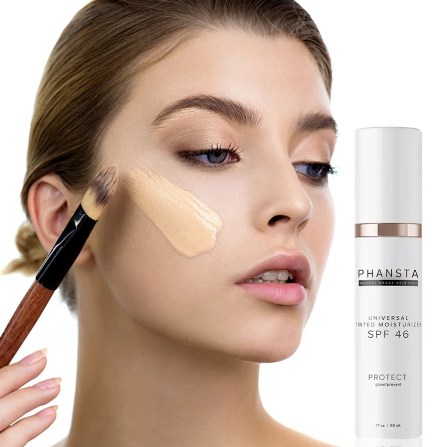 Woman applying concealer with a brush next to a bottle of Phansta skincare product.