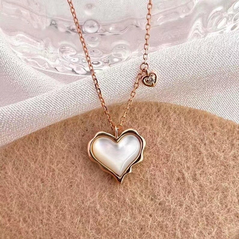 Heart-shaped necklace with a rose gold chain on a textured surface
