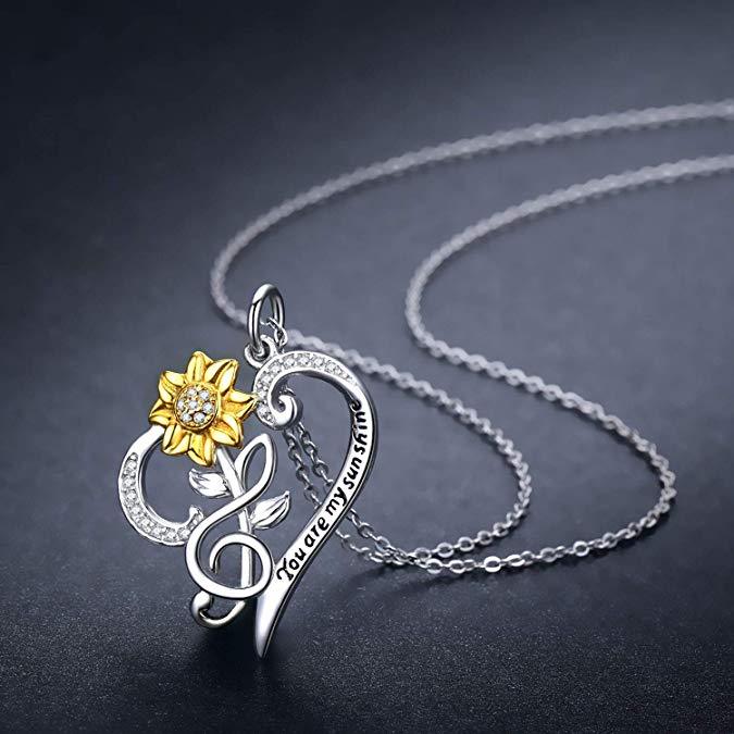 Necklace with a sunflower and music note pendant on a dark background