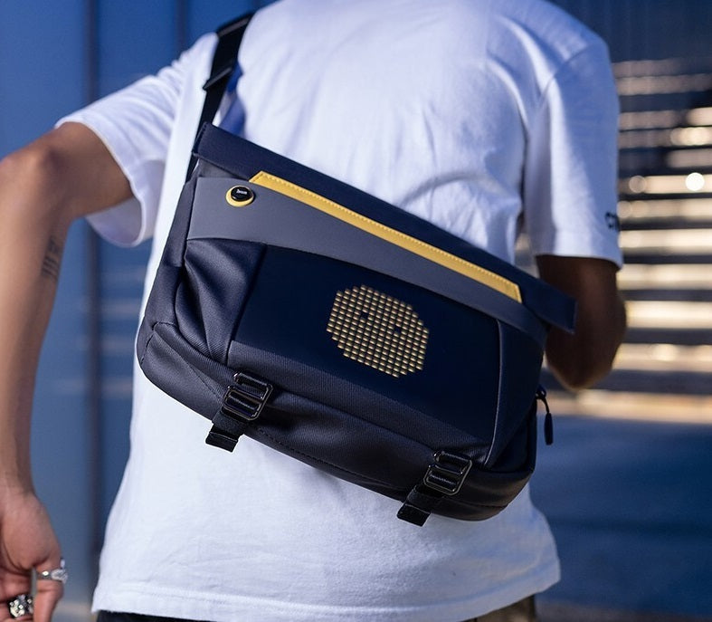 Person wearing a dark blue crossbody bag with a yellow stripe on a blurred background