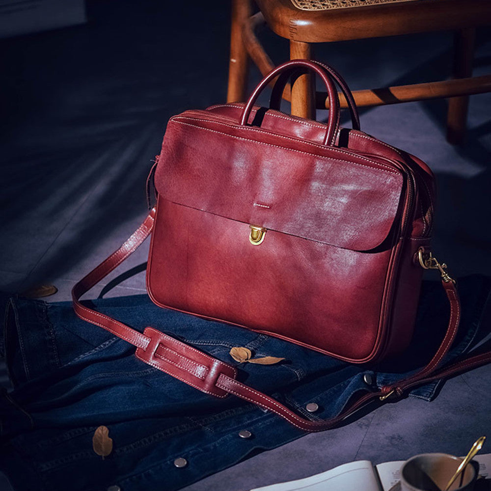 Red leather briefcase on a dark surface with a chair in the background