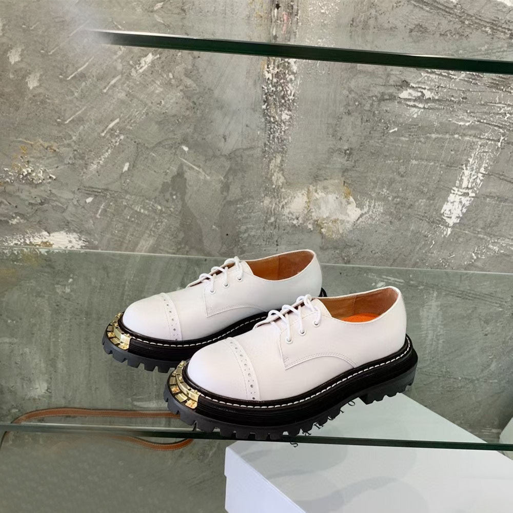 White shoes with black soles on a glass surface
