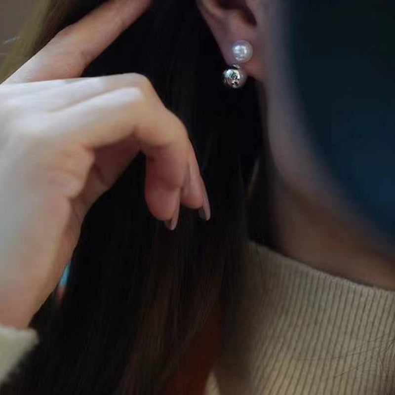 Close-up of a person wearing pearl earrings with a neutral background