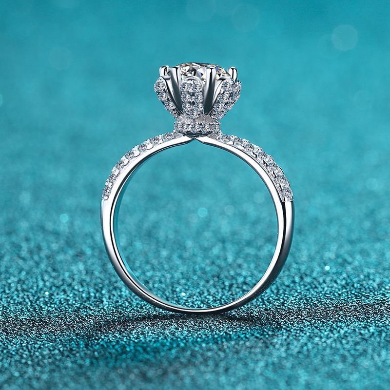 Silver diamond ring on a teal glittery background
