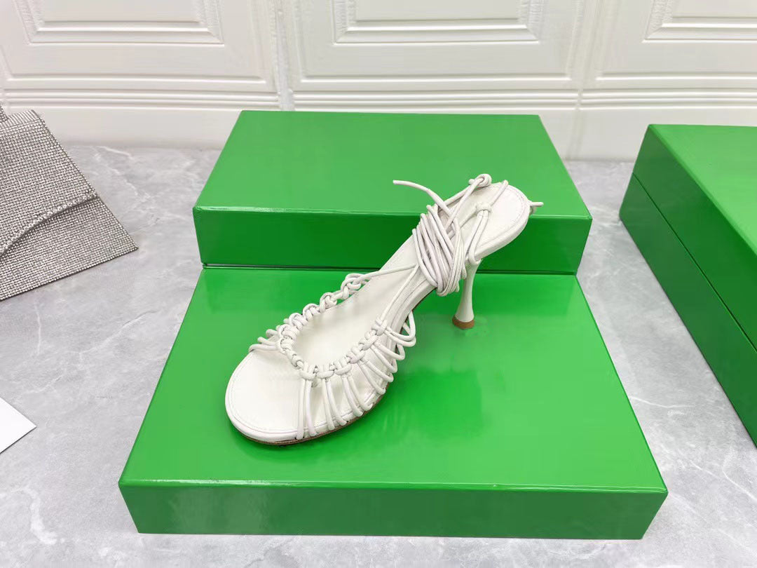 White high-heeled shoe on a green box with a white tiled wall background